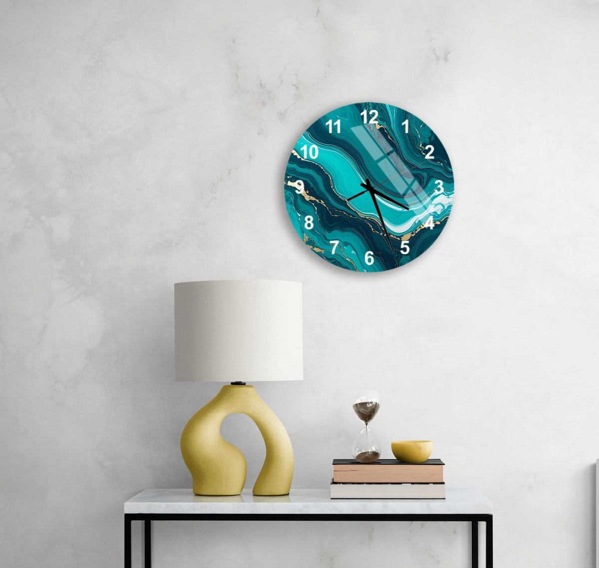 a modern living room with a white marble wall, a round wall clock with a turquoise marble design, a yellow lamp with a unique curved base, a stack of books, and a glass of wine on a white table.