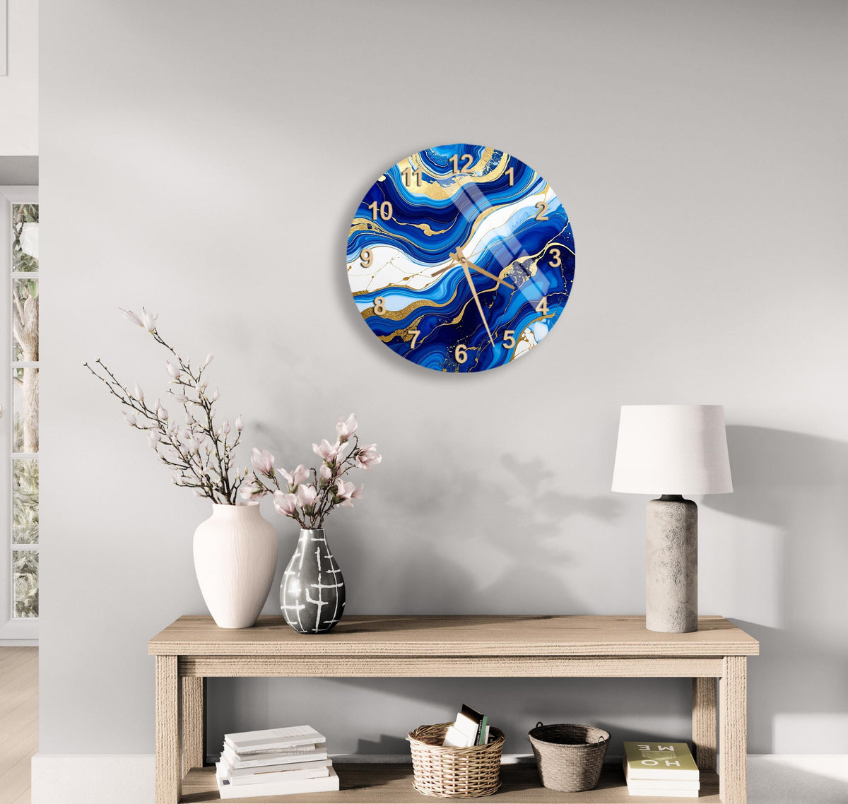 a modern living room with a wooden console table, a white vase with pink flowers, a lamp, and a clock with a blue and white marble design on the wall.