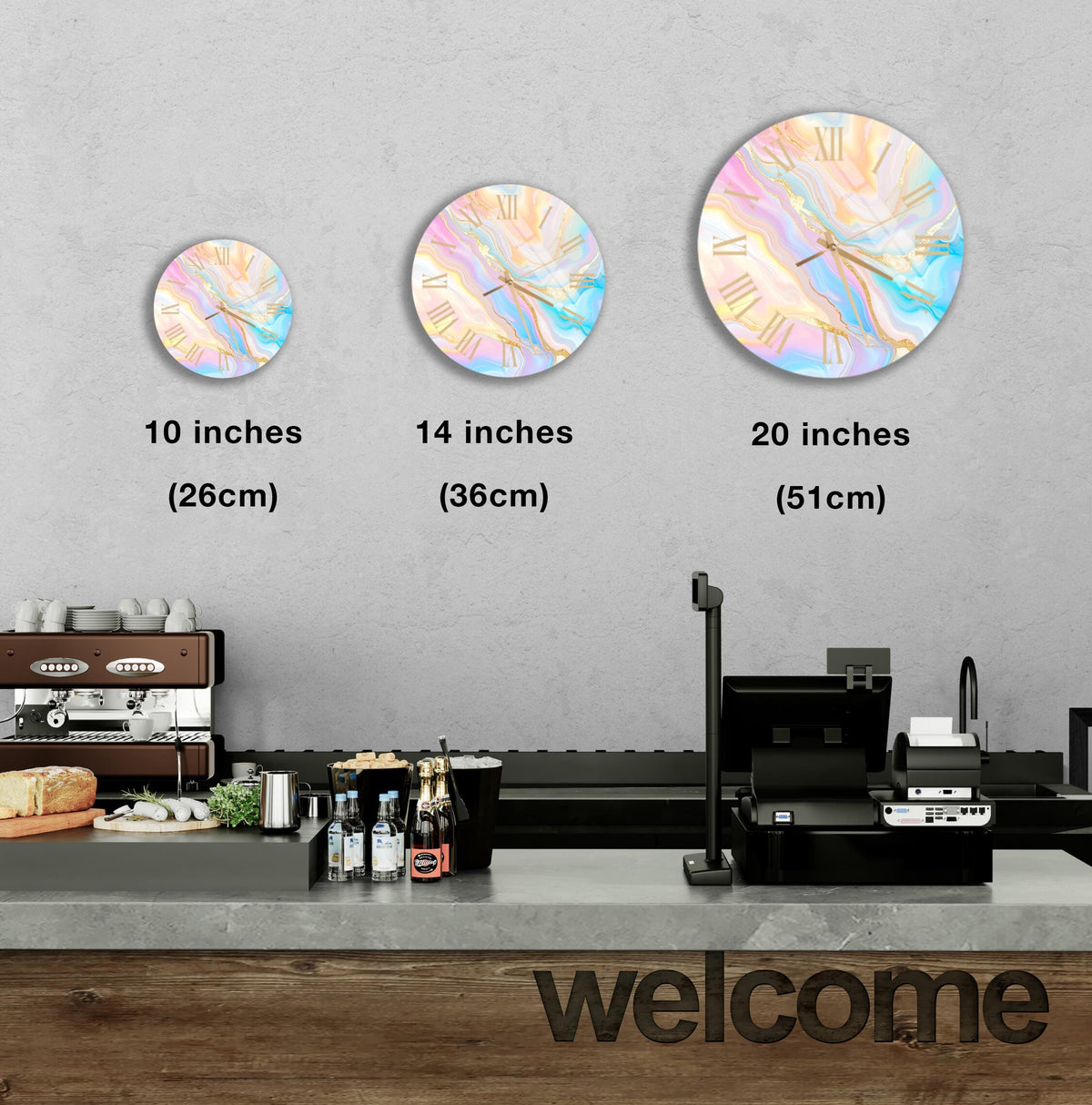 a wall with three clock designs of different sizes, and there is a counter with various items on it, such as bottles and a sandwich.