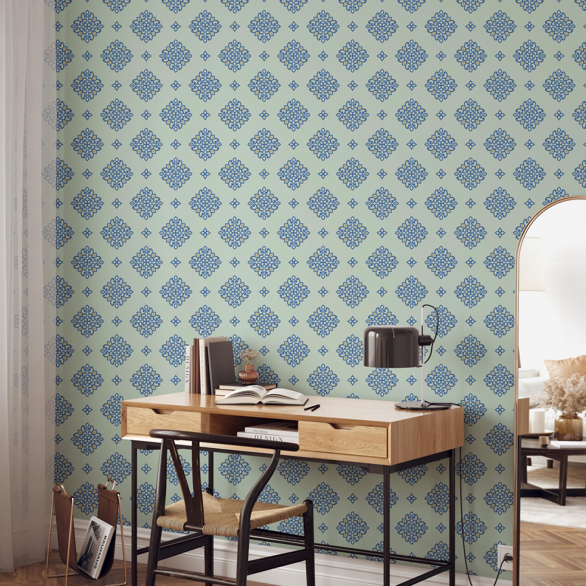 a modern workspace with a wooden desk, a black lamp, and a bookshelf. The wall behind the desk has a patterned wallpaper with blue and green designs.