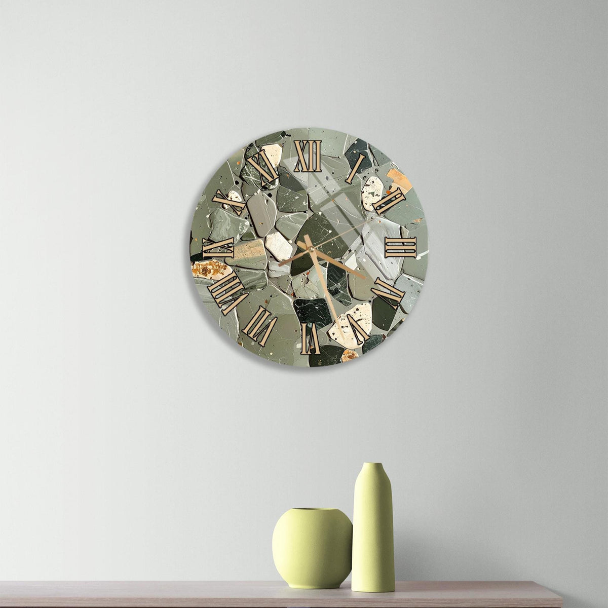 a modern clock with a mosaic design on a light-colored wall, accompanied by a wooden dresser and a small green vase.