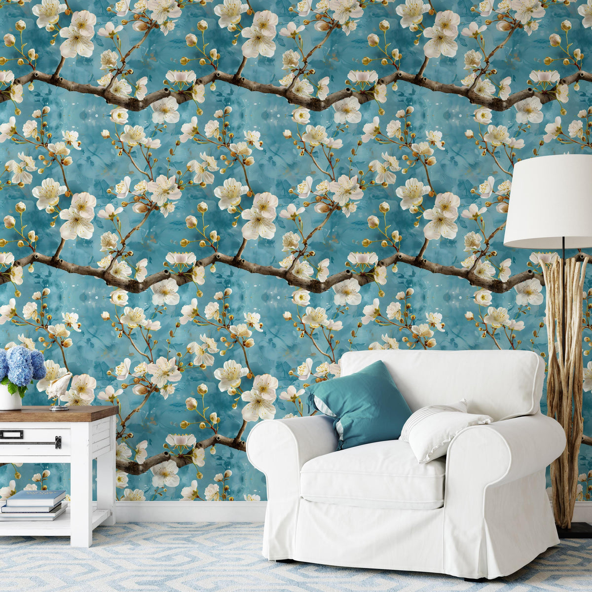 a living room with a white armchair, a wooden side table, and a lamp. The wall behind the furniture is covered in a floral wallpaper with white and yellow flowers.