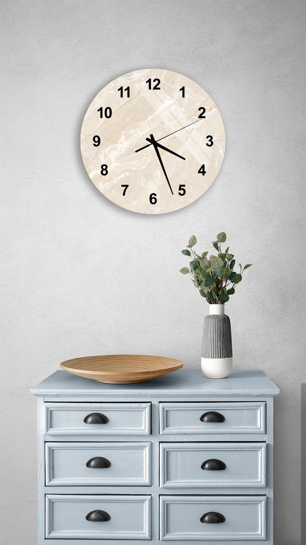 a light blue wooden dresser with a round clock mounted on the wall above it. The dresser has six drawers and a vase with greenery on top.