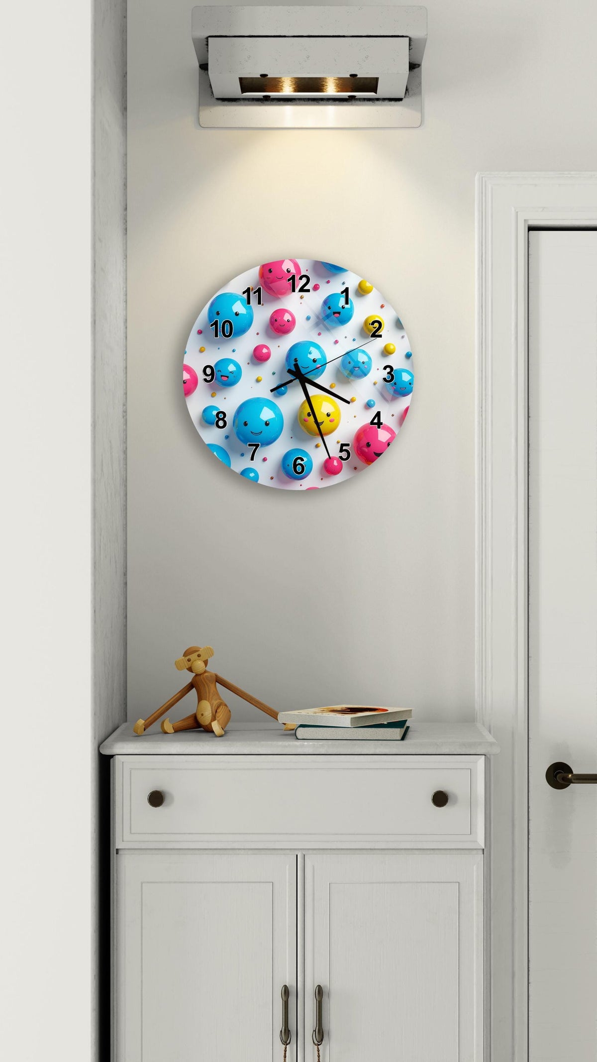 a wall clock with a colorful design of bubbles and numbers, mounted on a white wall above a white cabinet.