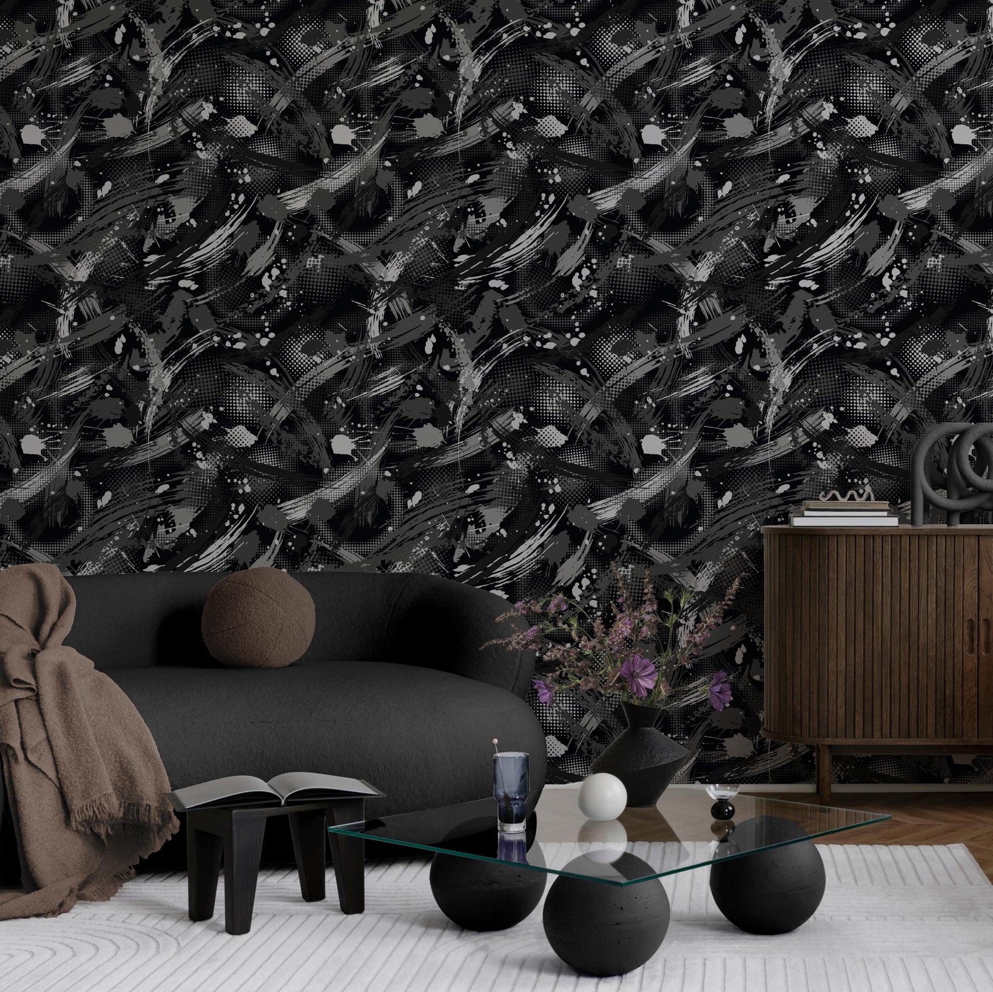 a modern living room with a black and white abstract wallpaper pattern, a gray sofa, a glass coffee table, and a wooden cabinet.