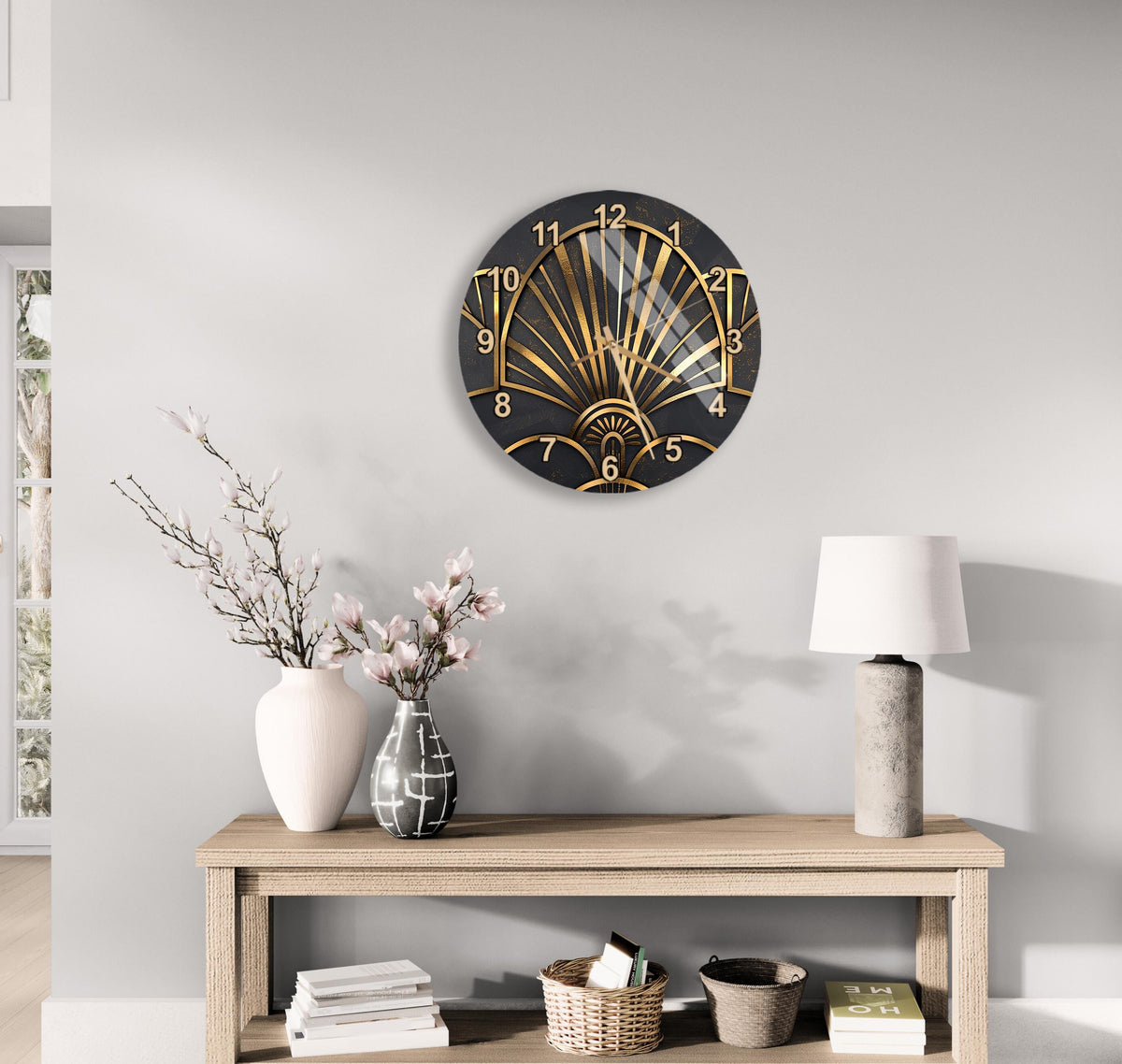 a modern black and gold clock with a fan-like design, mounted on a wall above a wooden table with a lamp and decorative items.